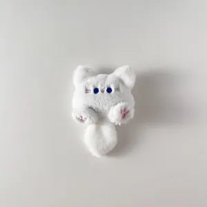 Dettaglio del ciondolo a forma di gatto in peluche bianco con ricamo di occhi azzurri