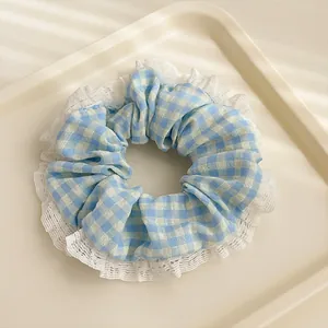 Détail d'un chouchou à carreaux bleus et blancs avec bordure en dentelle blanche