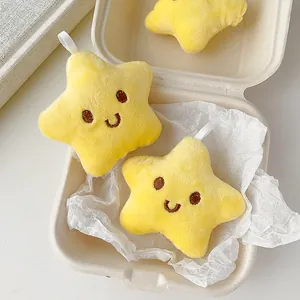 Detalle de tres colgantes de estrella de peluche amarillo con caras bordadas en una caja