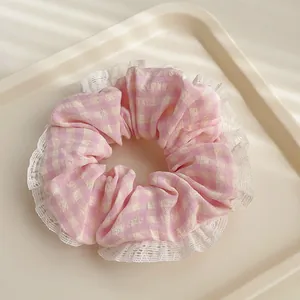 Gros plan d'un chouchou à carreaux roses avec bordure en dentelle blanche sur plateau