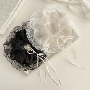 Close-up of black and white lace scrunchies with long ribbons on a minimalist display