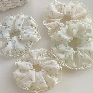 Detailed close-up of four floral scrunchies with elegant white lace edges on beige background
