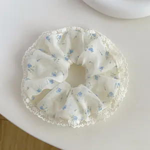 Close-up of floral scrunchie with blue pattern and white lace edge on a desk