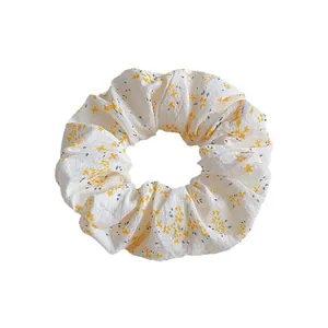 Floral print scrunchie in beige with yellow flower patterns for elegant hair styling
