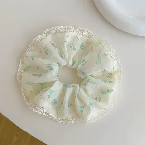 Detailed shot of floral mesh scrunchie with white lace trim and green flower patterns