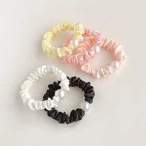 Gros plan de chouchous en satin à perles en jaune, corail, rose, blanc et noir