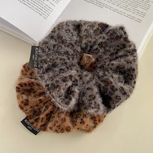 Retro plush leopard print scrunchies with Blind For Love woven labels on vintage book
