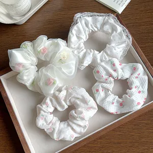 Ensemble détaillé de quatre chouchous blancs en dentelle avec broderie fleurie