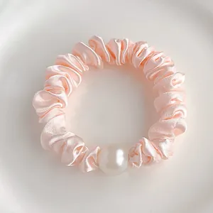 Vue macro détaillée d'un chouchou en satin rose clair orné d'une grande perle élégante