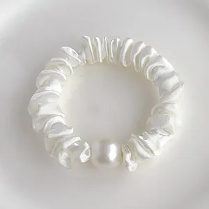 Détail macro du chouchou en satin blanc avec une grande perle brillante élégante
