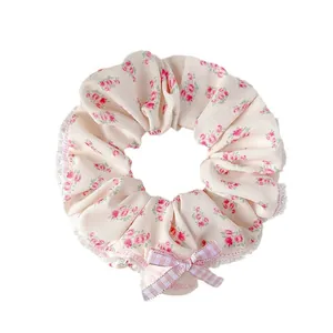 Chouchou floral avec motif roses roses et nœud vichy sur un fond blanc neutre