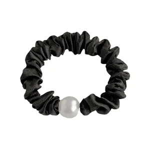 Chouchou élégant en satin noir avec perle blanche sur fond blanc immaculé