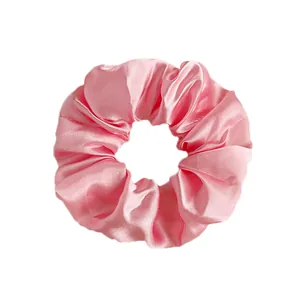 Pink satin scrunchie for ponytails with smooth silk-like texture on a white background