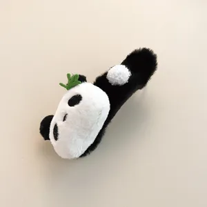 Close-up of plush panda hair claw clip with black and white fur and green leaf detail