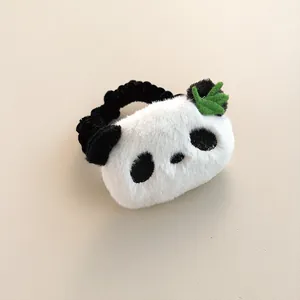 Detail of cute plush panda hair tie with soft black and white fur and green leaf embroidery