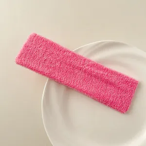 Detail of rose pink terry cloth sports headband on a white ceramic plate