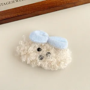 Dettaglio del fermaglio per capelli a forma di cane teddy in peluche con fiocco azzurro