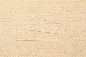 Dettaglio di tre spilli a testa piatta in argento S925 di diverse lunghezze per gioielli
