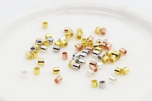 Macro shot of 1.5mm silver, gold and rose gold cylindrical crimp beads for jewelry DIY