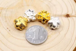 Makroaufnahme von 3D Lotus-Abstandshalterperlen in Gold und Silber mit Münze als Referenz