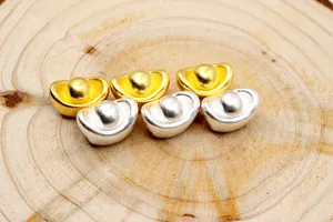 Makro-Detail von S999 Silber Yuan Bao Anhängern in Gold und Silber mattiert