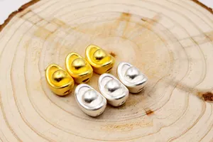 Nahaufnahme von Gold und Silber S999 Silber Yuanbao Perlen mit Loch auf Holzhintergrund