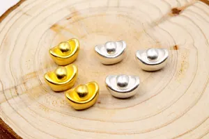 Makroaufnahme von S999 Sterling Silber Sycee-Perlen in Gold und Silber auf Holzgrund