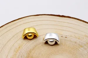 Makroaufnahme von 3D-Silber-Yuanbao-Anhängern in Gold und Silber matt auf Holz