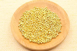 Detailed view of polished golden round beads for DIY jewelry making in a wooden bowl