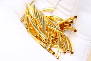 Macro detail of polished gold-plated S925 silver curved tube beads for DIY jewelry making