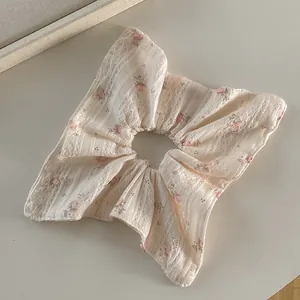 Vue détaillée du chouchou en dentelle crème avec de délicats motifs floraux roses