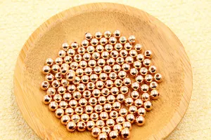 Macro shot of rose gold round metal beads with center holes in a wooden jewelry tray