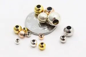 Macro shot of gold, silver and rose gold S925 sterling silver slider beads with coin size guide