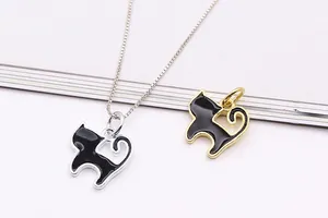 Dettaglio di ciondoli a forma di gatto in argento e oro con finitura in smalto nero