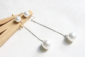 Dettaglio di orecchini pendenti in argento S925 con perle bianche e catene d'argento