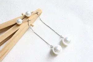 Dettaglio di orecchini pendenti in argento S925 con catena e doppie perle bianche