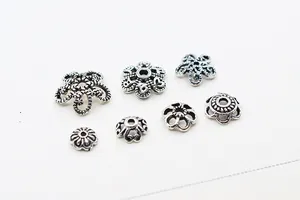 Detailed close-up of vintage silver flower bead caps and floral spacers for DIY jewelry