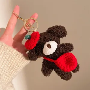 Détail d'un porte-clés ours en peluche marron avec bonnet rouge et petite sacoche