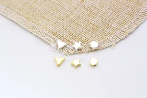Macro shot of silver and gold geometric spacer beads for jewelry making on linen background