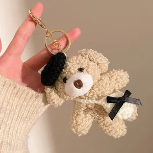 Détail d'un pendentif ours en peluche bouclée avec béret noir et petit sac à bandoulière