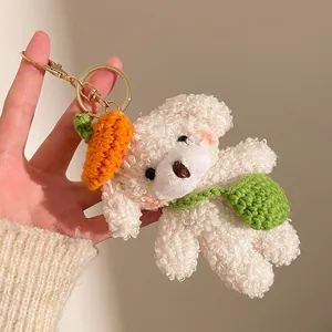 Détail d'un porte-clés chien en peluche blanc avec chapeau carotte et sac au crochet