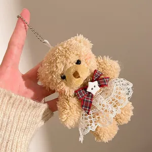 Gros plan d'un pendentif ours en peluche avec robe en dentelle et nœud à carreaux