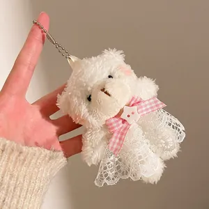 Détail d'un porte-clé ours en peluche blanc avec nœud vichy rose et jupe en dentelle