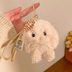 Close-up of a pink plush bunny keychain with a plaid hat and a pearl bow accessory