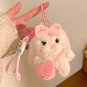Close-up of plush rabbit keychain with pink bow, knit bag, and soft textured fabric