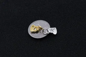 Dettaglio macro di ciondoli a cuore in oro e argento con cristalli accanto a moneta