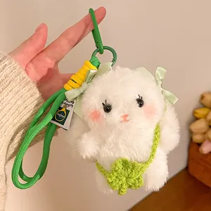Detail of white plush bunny keychain with green bows, clover bag and woven lanyard