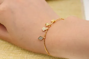 Detail van een gouden armband met met zirkonia bezette speelkaartbedeltjes in micro-pavé