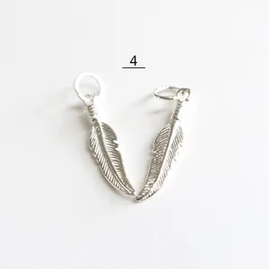 Dettaglio macro di ciondoli a piuma in argento S925 con trame di foglie per gioielli DIY
