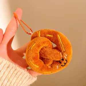 Gros plan d'un porte-clés bretzel en peluche avec visage souriant et chaîne orange